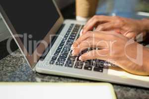 Cropped hands of businessman using laptop