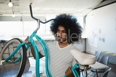 Man with curly hair holding bicycle at office