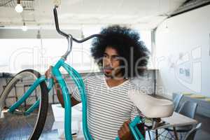 Man with curly hair holding bicycle at office
