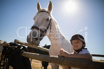 Smiling girl standing near the white horse in the ranch