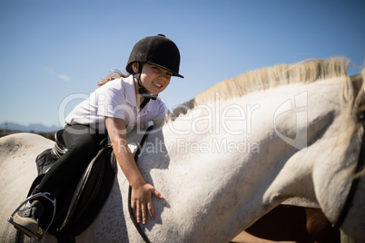 Smiling girl embracing the white horse in the ranch