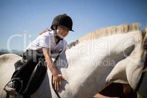 Smiling girl embracing the white horse in the ranch