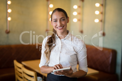 Smiling waitress using digital tablet in bar