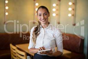 Smiling waitress using digital tablet in bar