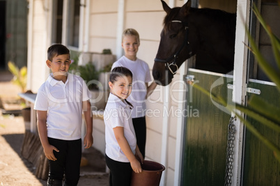 Smiling kids feeding the horse in stable