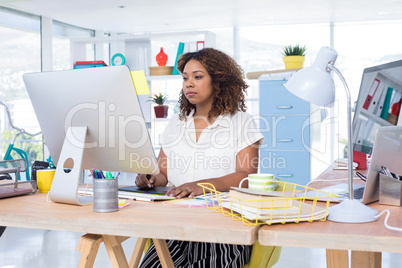 Female executive working over graphic tablet at her desk