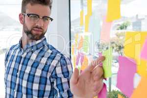 Male executive pointing at sticky note in office