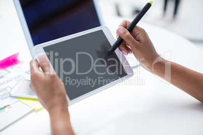 Hands of female graphic designer using graphic tablet at desk