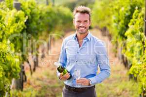Portrait of smiling man holding wine bottle and glass