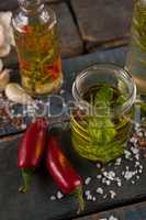 High angle view of jalapeno pepper by spices and herbs with oil in containers