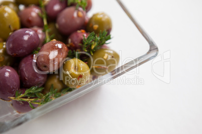 Cropped image of olives with thyme served in glass bowl