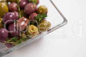 Cropped image of olives with thyme served in glass bowl