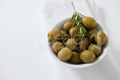 High angle view of green olives with rosemary in bowl