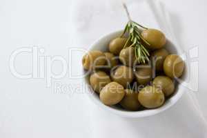 High angle view of green olives with rosemary in bowl
