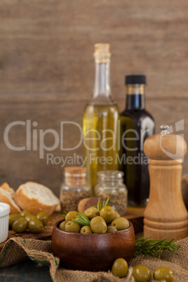 Green olives in bowl with oil bottles in background
