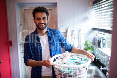 Portrait of smiling young man holding laundry basket