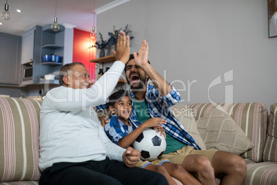 Happy family doing high five while watching soccer match