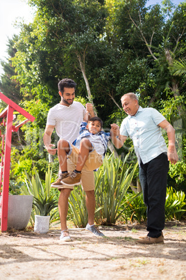 Playful father and grandfather with boy at park