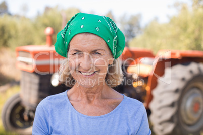 Portrait of happy woman standing against tractor in olive farm