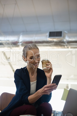 Businesswoman using mobile phone while sitting at table