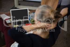 High angle view of businesswoman with hands behind head relaxing in office