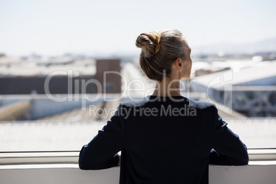 Rear view of thoughtful businesswoman looking through window