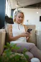 Woman using phone on sofa at office
