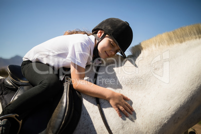 Smiling girl embracing the white horse in the ranch