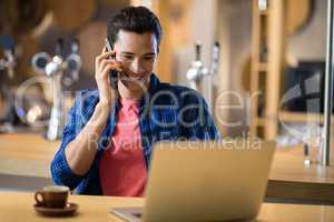 Man talking on mobile phone while using mobile phone in restaurant