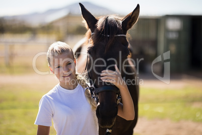 Smiling girl embracing the horse in the ranch