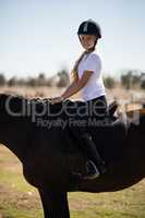 Smiling girl sitting on a horse in the ranch