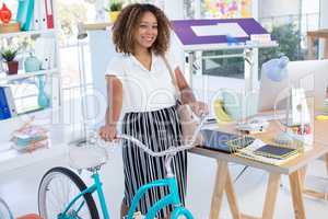 Female executive walking with bicycle in the office