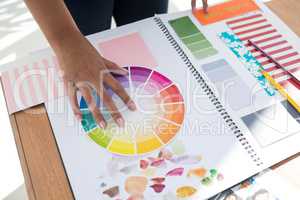 Graphic designer holding color swatch at desk