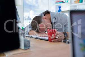 Tired male executive sleeping on desk