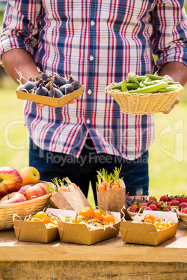 Midsection of young man selling figs and okras