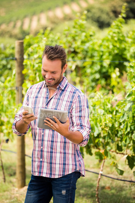 Smiling young man using tablet and phone