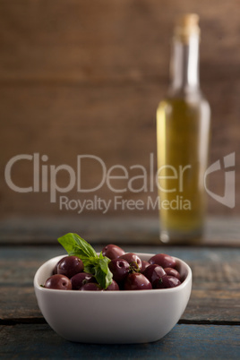 Black olive in container with bottle in background