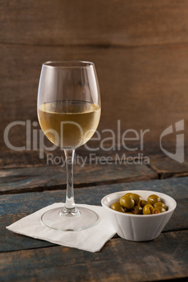 Green olives in container by white wine