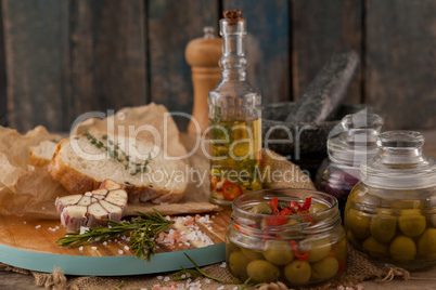 Green olives in glass jars with ingredients on table