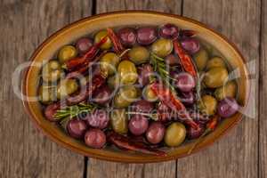 Overhead view of olives with oil and chili pepper in container