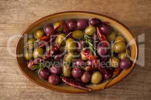 Olives and red chili pepper with oil in wooden container