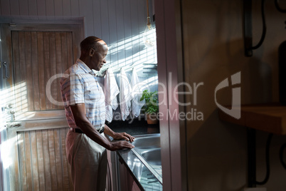 Side view of thoughtful man standing by sink