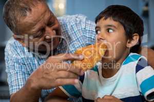 Grandfather feeding croissant to grandson