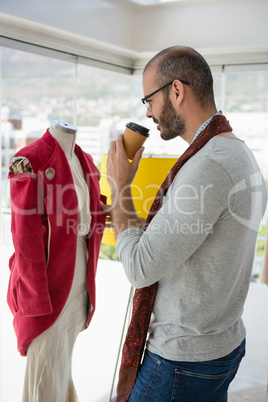 Designer examining clothes while drinking coffee