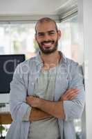 Portrait of smiling designer with arms crossed leaning on wall