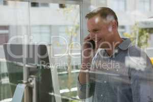 Smiling fashion designer talking on mobile phone seen through glass