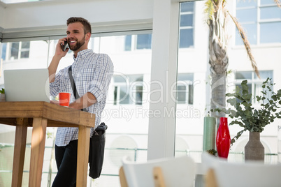 Businessman talking on mobile phone while standing at desk