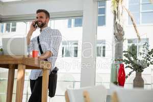 Businessman talking on mobile phone while standing at desk
