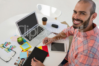 Portrait of graphic designer using tablet computer at desk in office