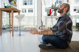 Side view of businessman meditating while sitting on floor